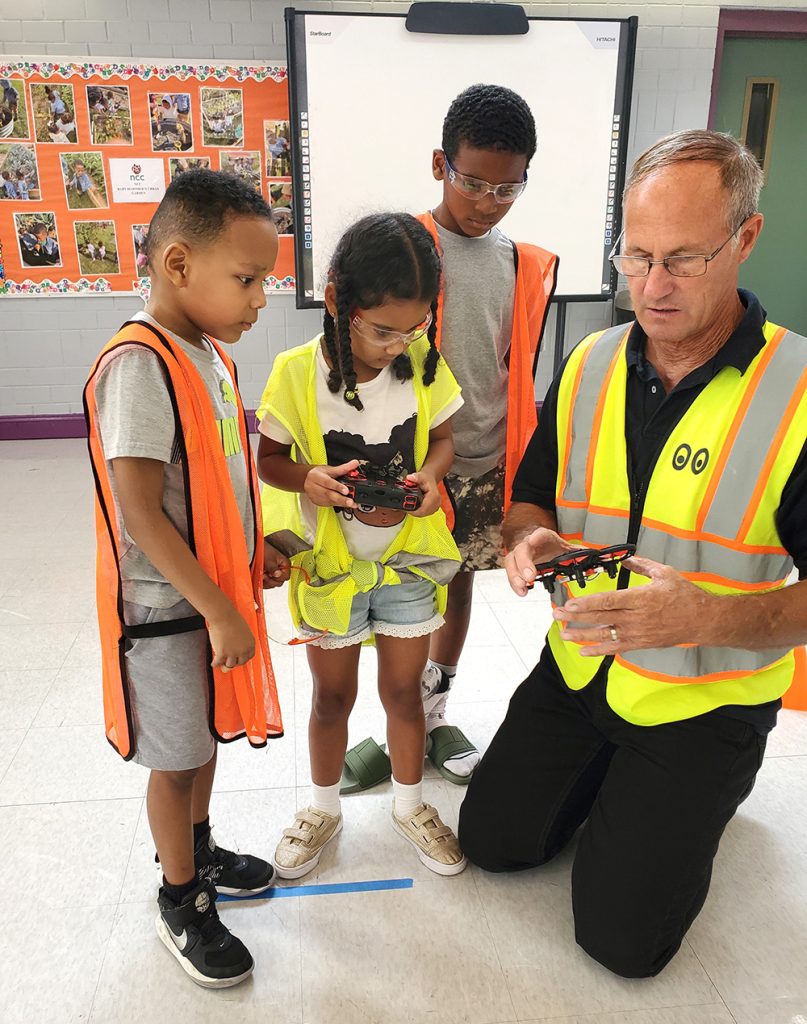 Young children learning how to operate a drone from a drone instructor